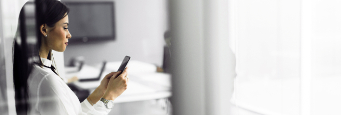 businesswoman looking at her smart phone in an office, display of Country Club Bank Business Mobile App