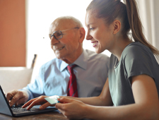 Older man and young woman working on a laptop photo